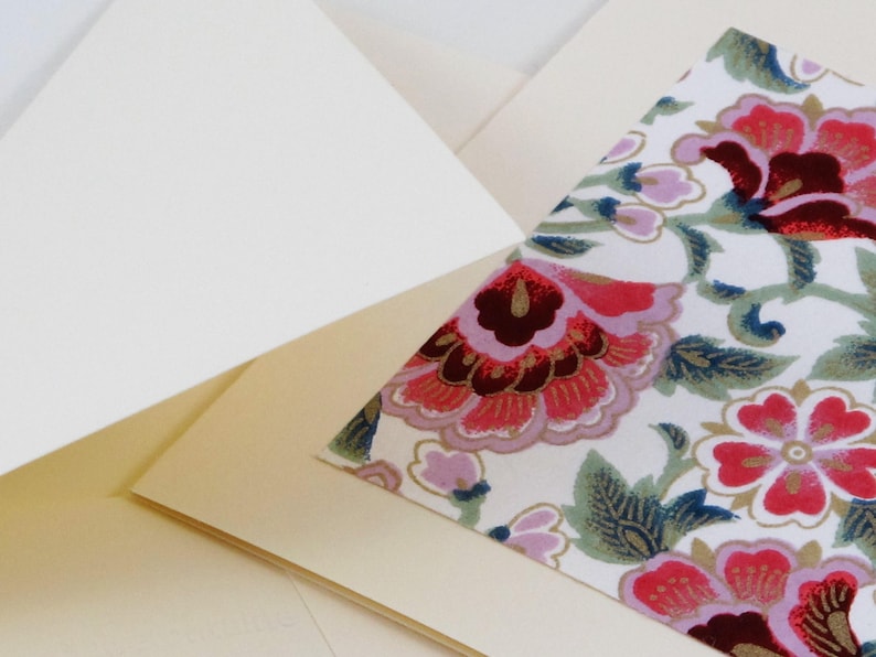 Puede incluir: Una tarjeta blanca con un dise&ntilde;o floral en la parte delantera. El dise&ntilde;o floral presenta flores rosas, rojas y verdes sobre un fondo blanco.