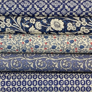 May include: Several rolls of fabric displaying a range of blue and white patterns. Designs include floral arrangements, stylized leaves, and geometric shapes. The fabrics are tightly rolled, showcasing the variety of patterns and textures.