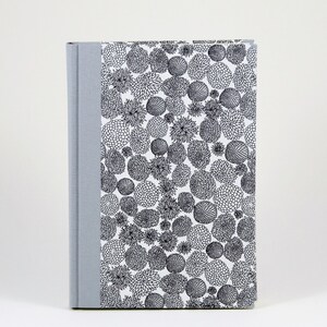 May include: A gray hardcover journal with a white cover featuring a black and white floral pattern.
