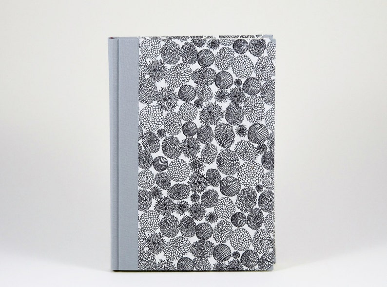 May include: A gray hardcover journal with a white cover featuring a black and white floral pattern.