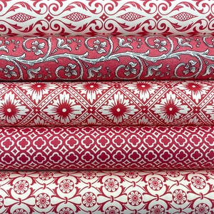 Puede incluir: Primer plano de varios rollos de papel estampado en rojo y blanco. Los diseños incluyen patrones florales, geométricos y de volutas. El papel está enrollado, mostrando la variedad de diseños.