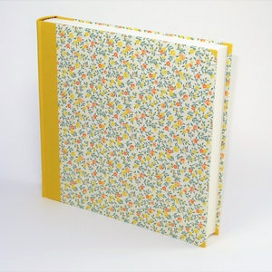 Puede incluir: Un &aacute;lbum de fotos de tapa dura con un patr&oacute;n floral amarillo y una columna vertebral amarilla.