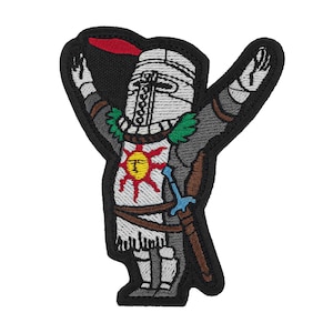 Può includere: Toppa ricamata raffigurante un cavaliere in armatura d'argento con un pennacchio rosso, con le braccia alzate in segno di lode. Il cavaliere ha un emblema solare sul petto e una spada di lato. La toppa ha un bordo nero.