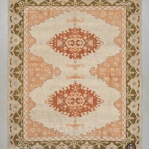 May include: A rectangular area rug featuring a cream-colored field with two large, symmetrical terracotta-colored central medallions. The rug has a wide border in olive green with floral motifs and a secondary peach-toned border with small flowers.