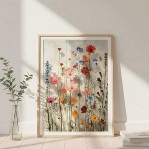 Großes Wandbild mit gepressten Wildblumen, skandinavisches Interior-Design im Flur. Angelehnt an eine helle Wand auf hellem Holzboden mit einer Glasvase und Büchern. Minimalistische, nordische Wohndeko.