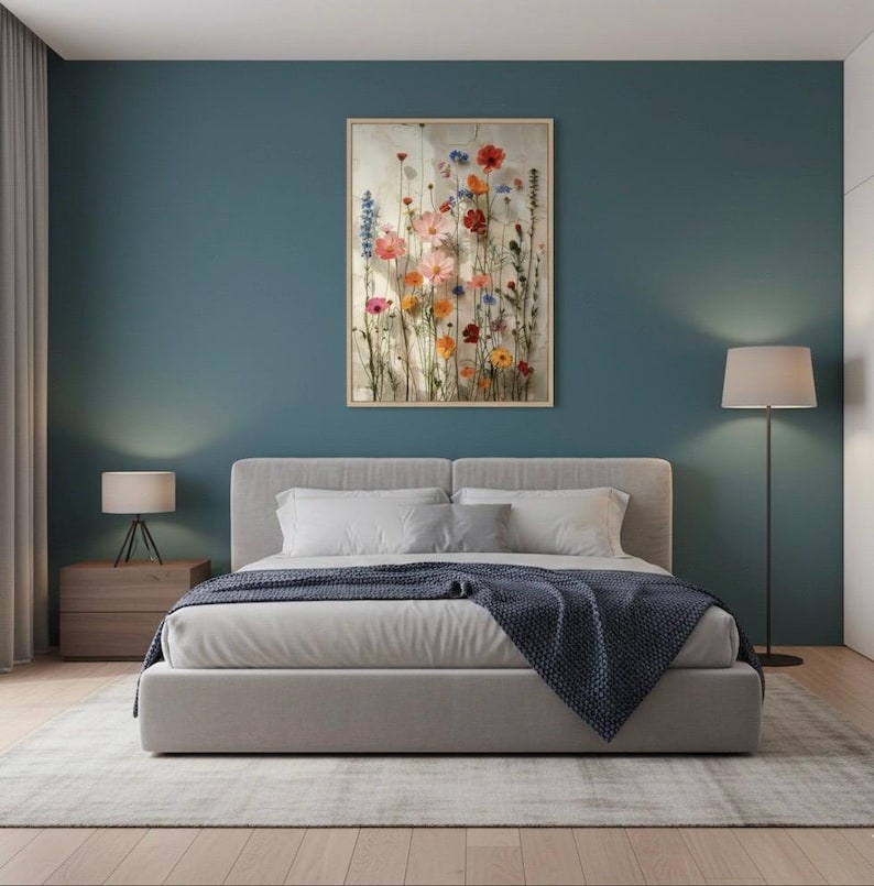 Modernes Schlafzimmer-Wandbild, hängend über einem Bett mit grauer Tagesdecke. Dunkelblaue Akzentwand, minimalistische Nachttischlampen und natürliches Licht. Ruhige und stilvolle Schlafzimmer-Dekoration.