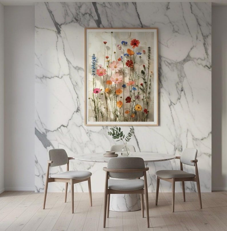 Eleganter botanischer Kunstdruck an einer edlen, marmorierten Wand im Esszimmer. Moderner Esstisch mit hellen Stühlen und floraler Tischdeko. Stilvolle Wandkunst für gehobenes Interior-Design.
