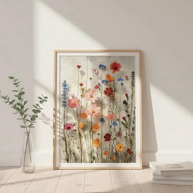 Großes Wandbild mit gepressten Wildblumen, skandinavisches Interior-Design im Flur. Angelehnt an eine helle Wand auf hellem Holzboden mit einer Glasvase und Büchern. Minimalistische, nordische Wohndeko.