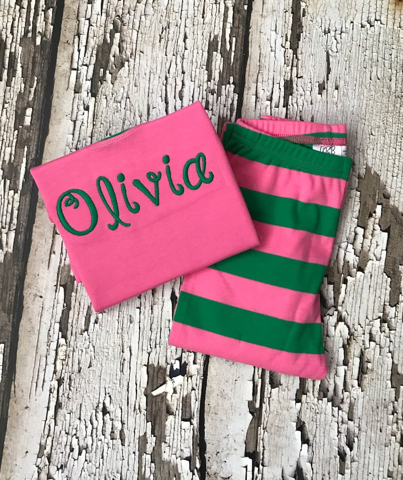 May include: Pink and green striped pajamas with the name Olivia embroidered on the pink top.