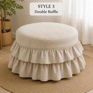Pode incluir: Um pufe redondo bege com uma base de folho duplo. O tecido tem uma textura entrela&ccedil;ada. Uma etiqueta acima do pufe exibe o texto STYLE 3 Double Ruffle. O pufe est&aacute; posicionado sobre um tapete redondo tran&ccedil;ado.