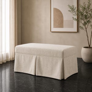 May include: A rectangular upholstered bench featuring a light beige fabric cover with a structured, pleated skirt base. The bench has a flat, cushioned top surface and a clean, tailored design that extends down to the floor in a skirted style.