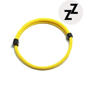 May include: A bright yellow rope bracelet with black connectors. The bracelet is circular and has a textured appearance. A white circle with the black letter "Z" repeated twice is in the upper right corner.