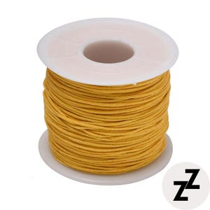 May include: A spool of yellow waxed cord. The cord is tightly wound around a white plastic spool. The spool has a central hole and a wide, flat base. The cord appears to be made of a durable material, suitable for various crafting projects.