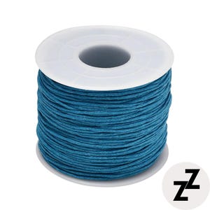 May include: A spool of teal-colored cord. The cord is tightly wound around a white plastic spool. The image is set against a white background. A black and white logo is in the bottom right corner.