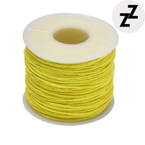 May include: A spool of bright yellow waxed thread. The thread is tightly wound around a white plastic spool. The spool has a white base and a white top with a central opening. A small, white circle with the letter "z" repeated twice is in the upper right corner.