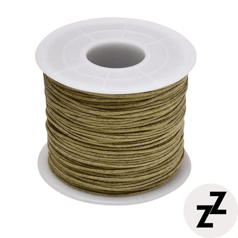 May include: A spool of olive green waxed cord. The cord is tightly wound around a white plastic spool. The spool has a circular base and a central hole. The image is on a white background. A black and white logo is in the bottom right corner.