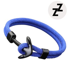 May include: Blue rope bracelet with a black anchor clasp. The bracelet features a woven design and a black metal anchor. A white circle with the letter "Z" is in the upper right corner.