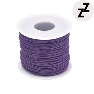 May include: A spool of purple cord, tightly wound around a white plastic core. The cord is a deep, saturated purple. A circular logo with the letter "Z" is in the upper right corner.
