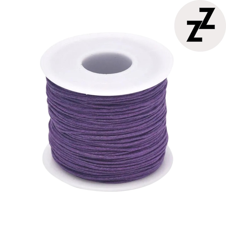 May include: A spool of purple cord, tightly wound around a white plastic core. The cord is a deep, saturated purple. A circular logo with the letter "Z" is in the upper right corner.