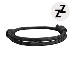 May include: Black bracelet made of woven cord. The bracelet is knotted at both ends. A white circle with the black letter "Z" repeated twice is in the upper right corner.