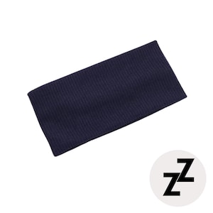 Könnte beinhalten: Ein marineblaues Stirnband aus Rippstrick. Das Stirnband ist rechteckig und hat eine strukturierte Oberfläche. Ein weißer Kreis mit den schwarzen Buchstaben "zz" befindet sich in der unteren rechten Ecke.