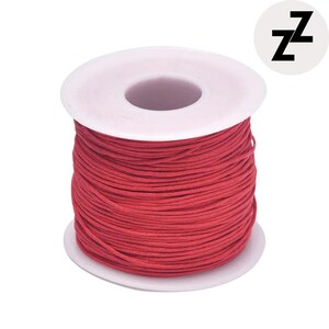 May include: A spool of red waxed cord. The cord is tightly wound around a white plastic spool. The spool has a central hole and a circular base. A logo with the letter "Z" is in the upper right corner.
