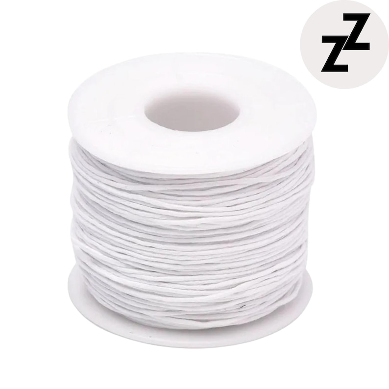 May include: A spool of white waxed cotton cord. The cord is tightly wound around a white plastic core. The spool has a circular shape with a central hole. A black and white logo with the letter "Z" is in the upper right corner.