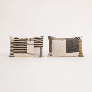 Pode incluir: Dois almofadas retangulares com design de patchwork. A almofada da esquerda apresenta riscas horizontais pretas e brancas, enquanto a da direita combina painéis de tecido em creme, cinzento escuro e riscas com uma textura de tecido visível.
