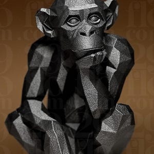Puede incluir: Una escultura geométrica negra de un mono en posición sentada, con la mano apoyada en la barbilla. La escultura tiene un diseño facetado, lo que le da una apariencia moderna y angular. Los rasgos faciales del mono son detallados, y la estética general es elegante y contemporánea.