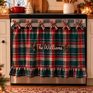 Può includere: Una copertura per fornelli con motivo scozzese rosso, verde e bianco e bordo inferiore arricciato. Il tessuto è fissato con sei piccoli fiocchi scozzesi sulla parte superiore. Al centro è ricamato il testo The Williams con decorazioni di agrifoglio.