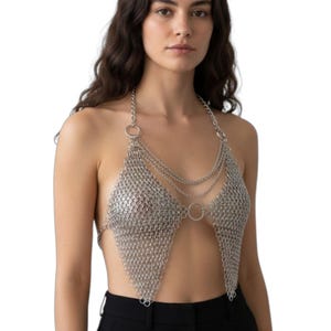 Puede incluir: Top halter de cota de malla plateada con dise&ntilde;o triangular. El top presenta m&uacute;ltiples hilos de cadena y detalles circulares. La prenda est&aacute; hecha de peque&ntilde;os anillos met&aacute;licos entrelazados.