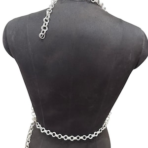 Puede incluir: Conjunto de cintur&oacute;n y collar de cadena plateada. El collar es de estilo gargantilla y el cintur&oacute;n est&aacute; dise&ntilde;ado para llevarse alrededor de la cintura. Las cadenas est&aacute;n hechas de eslabones circulares conectados. El conjunto se muestra en un maniqu&iacute; negro.