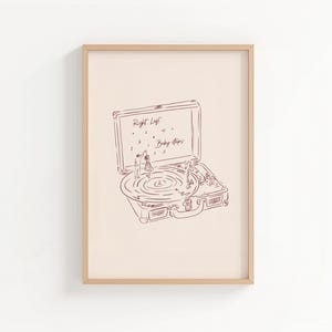 Könnte beinhalten: Ein gerahmter Druck mit einer Strichzeichnung eines Vintage-Plattenspielers, auf dem ein Paar tanzt. Der Text "Right Left Baby Steps" befindet sich über dem Plattenspieler. Das Kunstwerk ist in Braun- und Beigetönen gehalten.