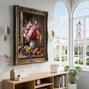 May include: A framed oil painting depicts a vibrant floral arrangement in a blue and white vase, with a still life of fruit. The painting hangs above a wooden console table with books and decor. Gold leaf sconces flank the artwork.