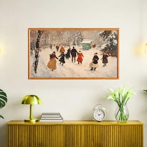 May include: A framed print of a winter scene with people playing in the snow. The artwork features figures in coats and dresses, set against a snowy landscape with trees and a small building. The frame is made of wood.