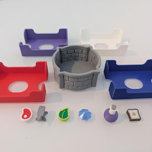 May include: A collection of colorful, 3D-printed game accessories. Includes red, purple, white, and blue card holders, a gray well, and miniature food and object tokens. The tokens include a steak, fish, leaf, umbrella, potion, and toast.