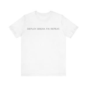 Może przedstawiać: Biała koszulka z czarnym napisem "DEPLOY. BREAK. FIX. REPEAT." umieszczonym centralnie na klatce piersiowej. Koszulka ma krótkie rękawy i okrągły dekolt.
