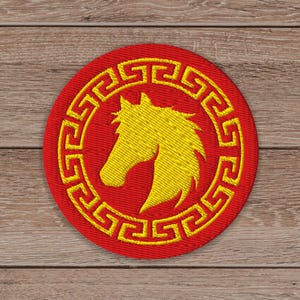 May include: A round, embroidered patch with a red background and a yellow horse head silhouette. The horse is surrounded by a yellow Greek key border. The patch is likely for clothing or accessories.