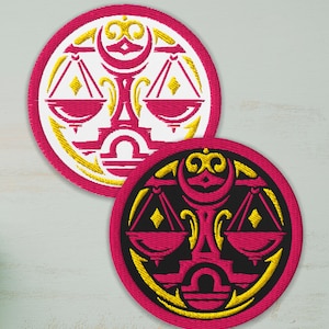 Op de afbeelding: Twee ronde geborduurde patches met het sterrenbeeld Weegschaal. De patches hebben een roze rand, met een witte of zwarte achtergrond. Het Weegschaal-symbool is roze en goudkleurig, met weegschalen en een maan.
