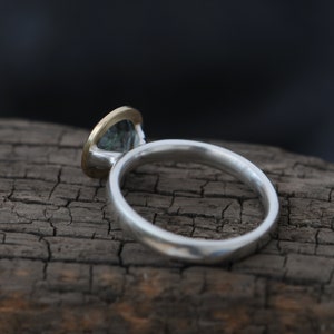 Puede incluir: Un anillo de plata con engaste de oro y una piedra preciosa verde.