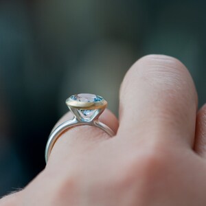 Puede incluir: Un anillo de plata con una banda de oro y una piedra preciosa azul.