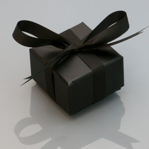 Puede incluir: Una caja de regalo negra con una cinta negra atada en un lazo.