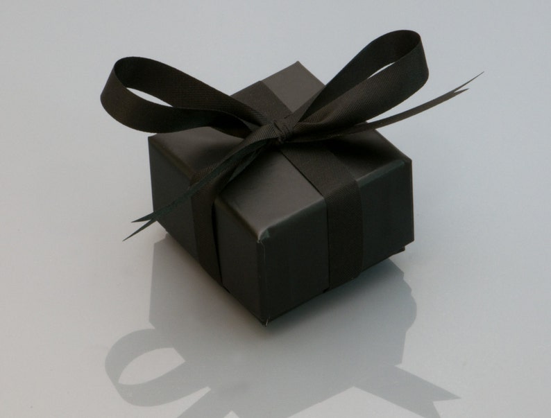 Puede incluir: Una caja de regalo negra con una cinta negra atada en un lazo.