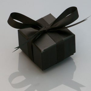 May include: A black gift box with a black satin ribbon tied in a bow.
