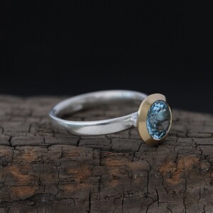 Puede incluir: Un anillo de plata con engaste de oro y una piedra preciosa azul.