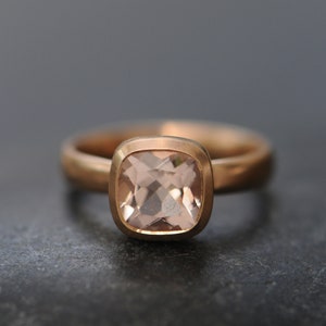 May include: A rose gold ring with a square-shaped, light pink gemstone.
