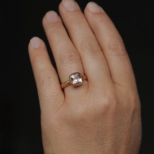 May include: A gold ring with a square-shaped clear gemstone.