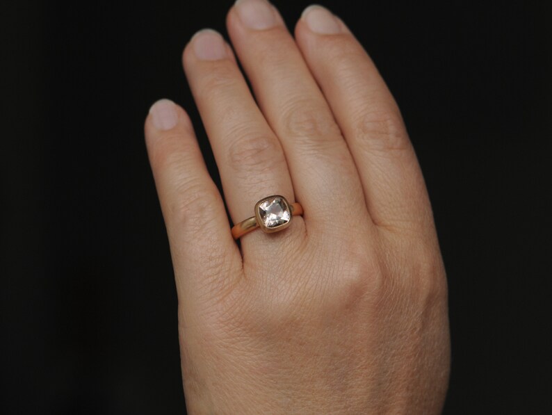 May include: A gold ring with a square-shaped clear gemstone.