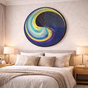 May include: A circular artwork with an abstract design in blue, yellow, and purple hangs above a bed. The bedroom has a neutral colour scheme, bedside lamps, and a potted plant, creating a calm atmosphere. The artwork is a striking focal point.