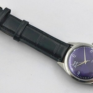 May include: A vintage wristwatch with a dark purple face and silver hands and casing. The watch has a black leather band with a silver buckle. The watch face has white numerals and text.